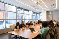 Conference room with people meeting and smiling with laptops